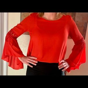 Red blouse with lace detail and bell sleeves.